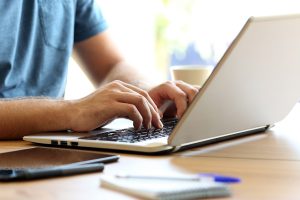 un hombre practica home office con su ordenador portátil