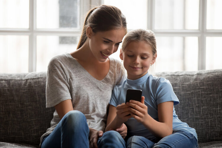 una madre y su hija usan un celular