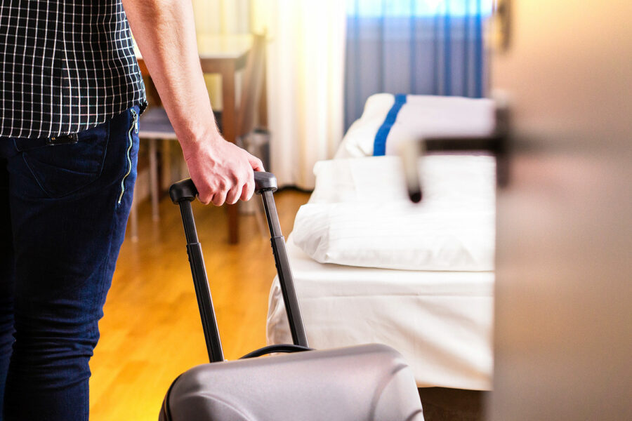 un hombre entra con su maleta en la habitación de un hotel