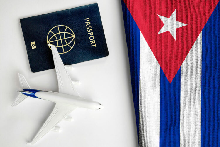 un pasaporte junto a un avión en miniatura y la bandera de Cuba