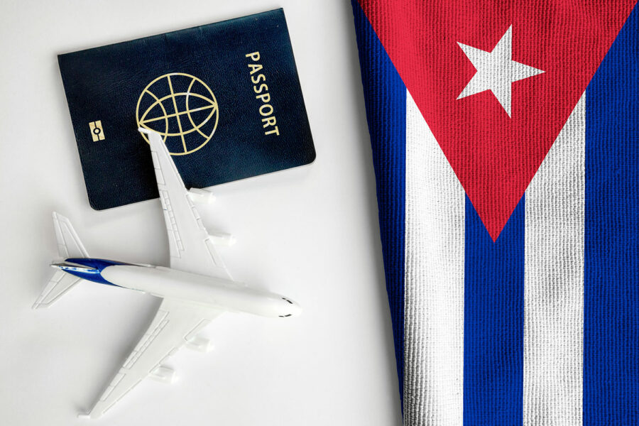 un pasaporte junto a un avión en miniatura y la bandera de Cuba