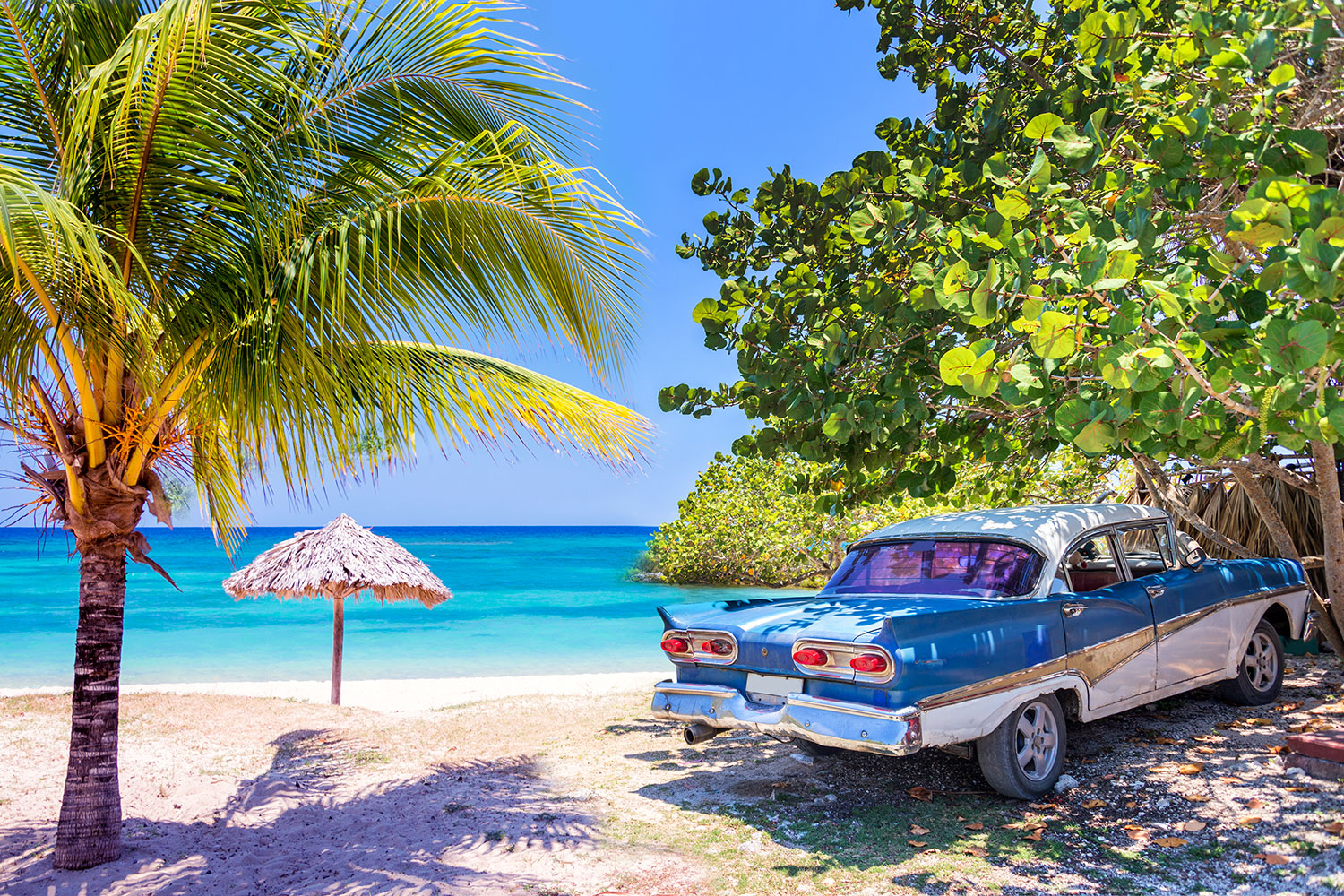 un coche antiguo junto a una playa cubana