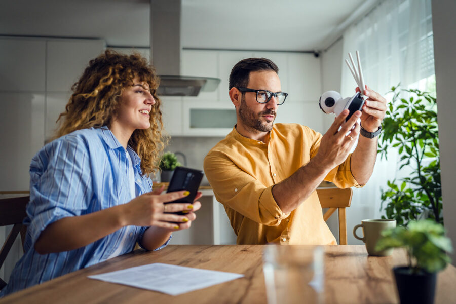 Una pareja consulta las instrucciones de una cámara de seguridad wifi antes de instalarla en su vivienda