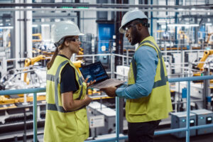 Dos trabajadores de una planta de automóviles con un ordenador portátil