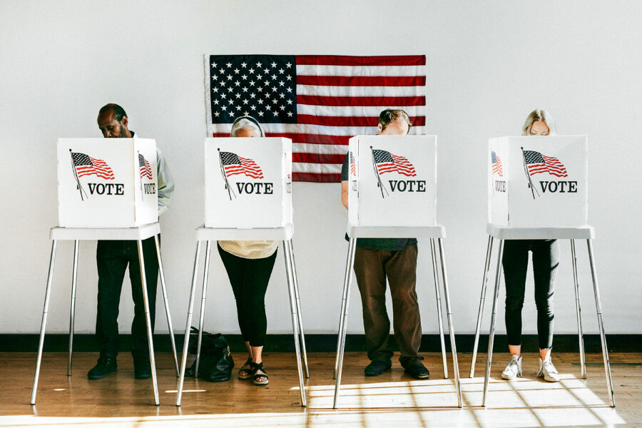 cuatro personas votan en un colegio electoral de Estados Unidos