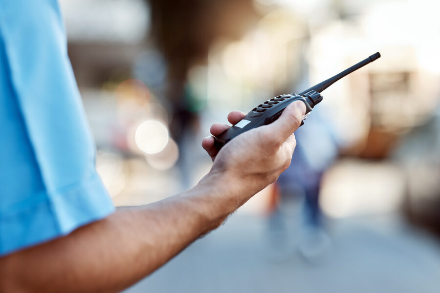 un guardia de seguridad privada sostiene un walkie talkie en su mano derecha