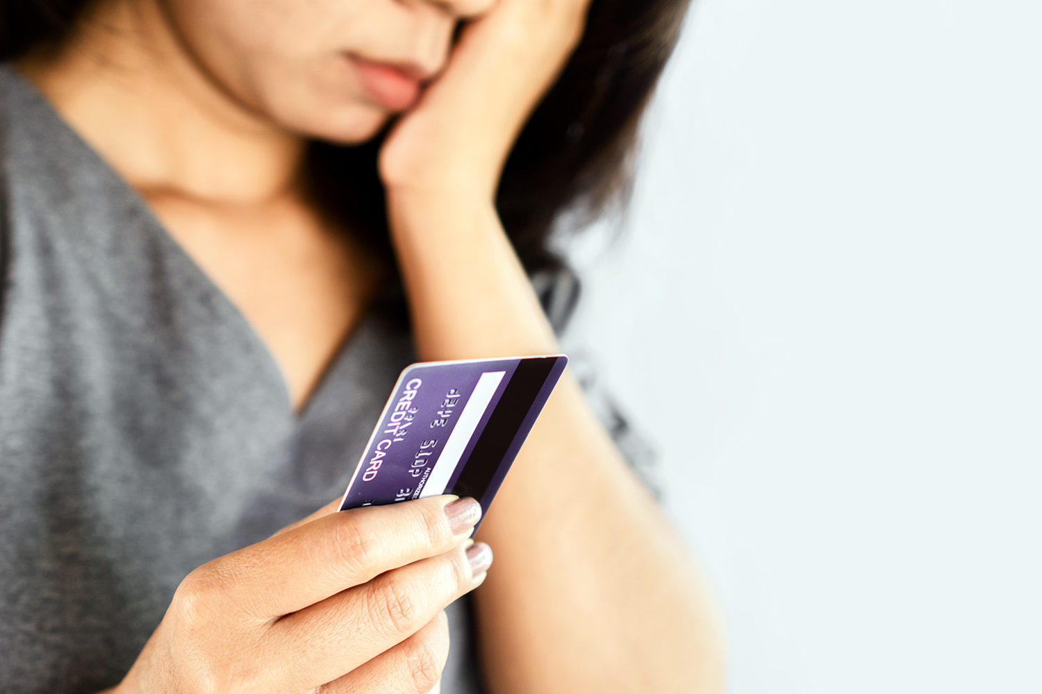 una mujer preocupada sostiene una tarjeta de crédito en su mano