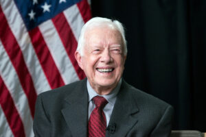 El presidente Jimmy Carter sonríe. Tras él, la bandera de Estados Unidos