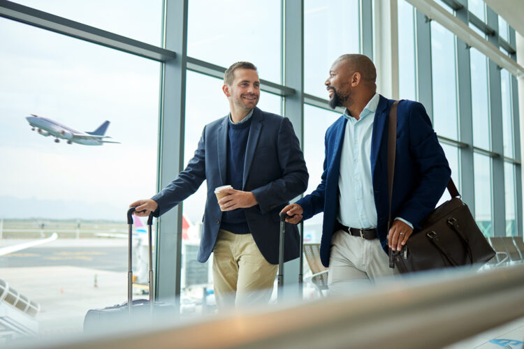 dos viajeros de negocios conversan en el aeropuerto mientras un avión despega